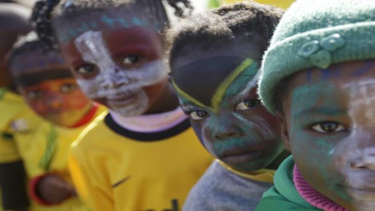 Uns nens amb la cara pintada esperen en fila per veure una rèplica del trofeu exposat a Soweto.