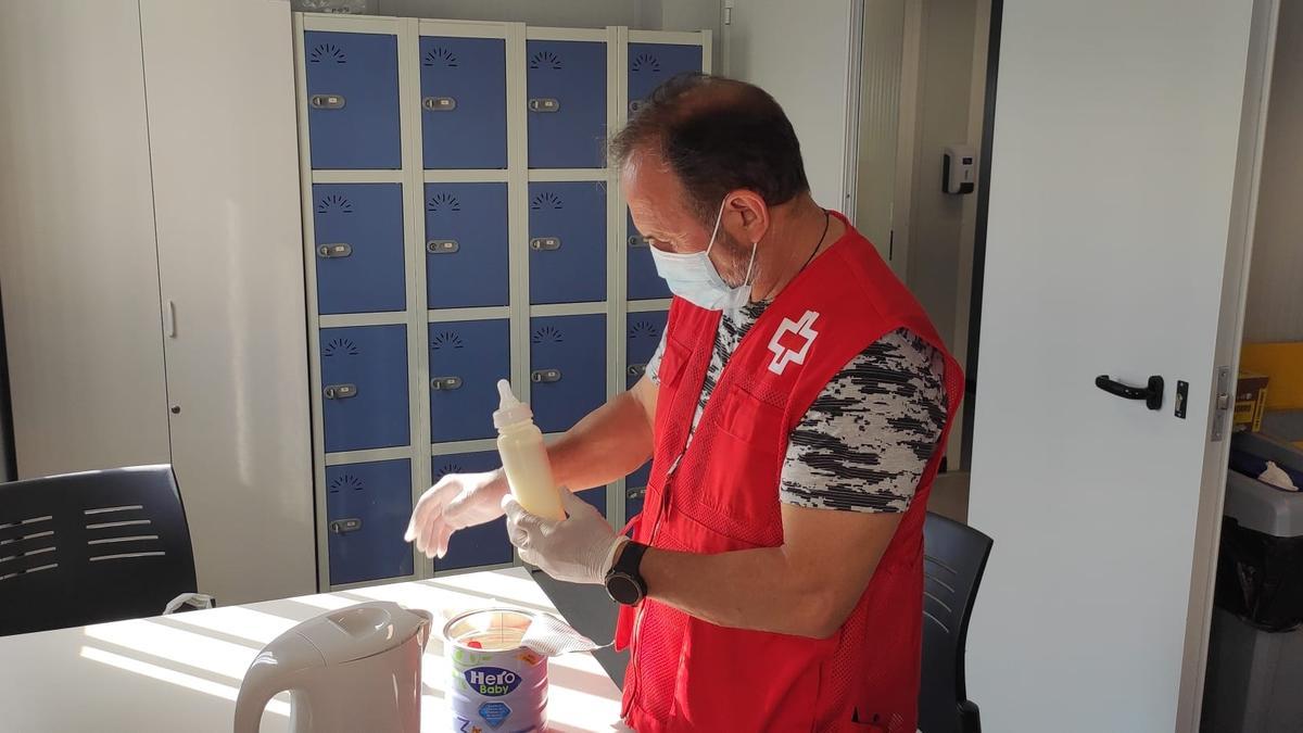 Un miembro de Cruz Roja prepara en Alicante un biberón para el bebé rescatado.