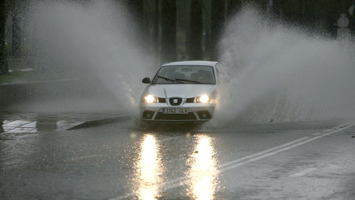 Un coche circula bajo una intensa lluvia.