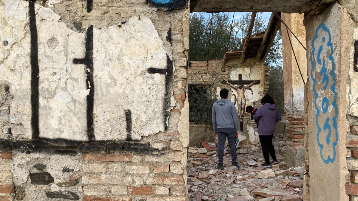 Dos paseantes se detienen ante la imagen del Cristo del Amor pintada en el muro de la casa en ruinas.