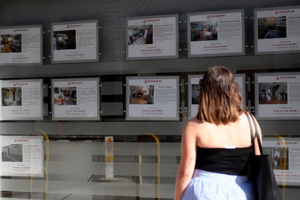 Una joven mira pisos de alquiler en el escaparate de una inmobiliaria de Murcia.