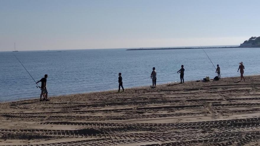 Pescadores de caña en la orilla de la playa de la Marineta Cassiana de Dénia