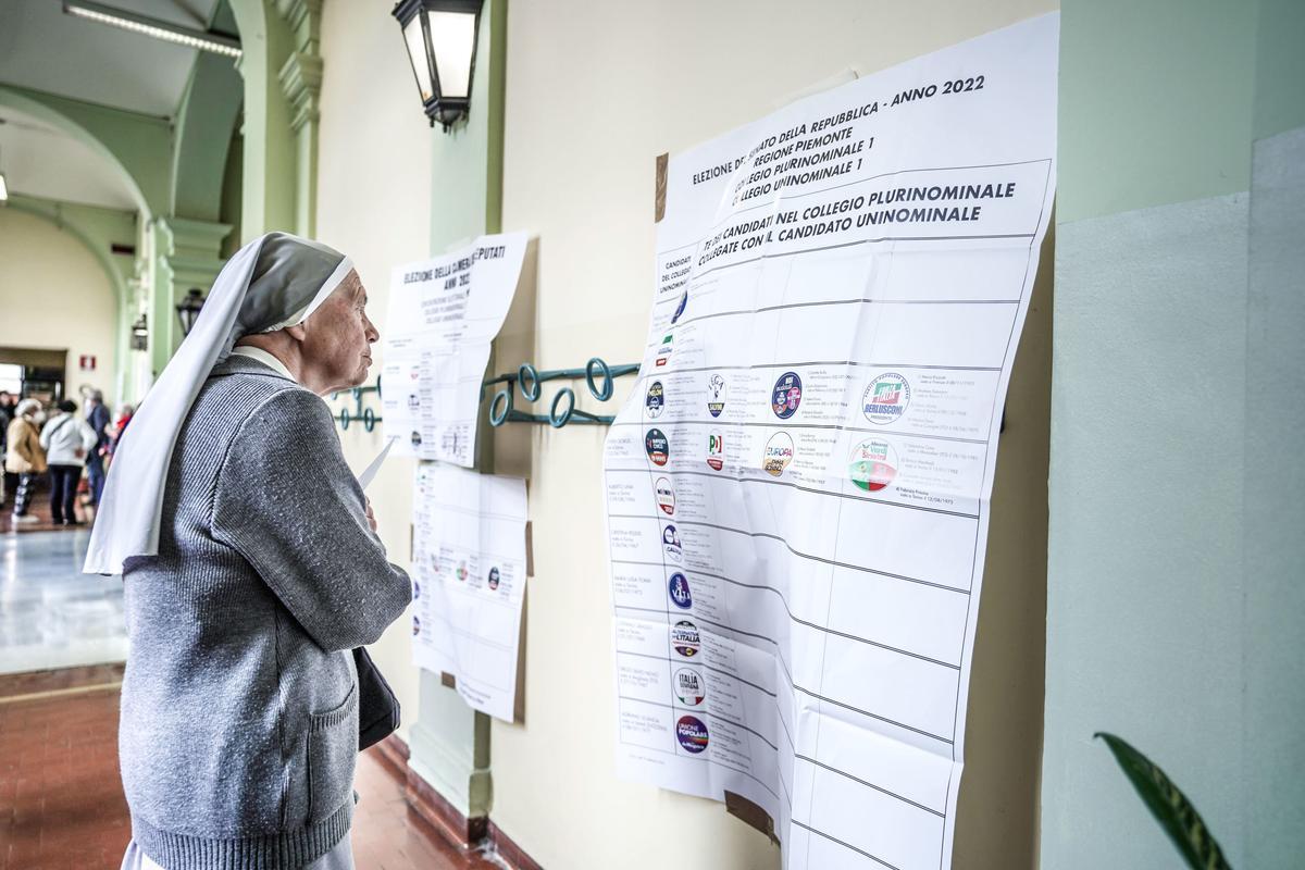 Una monja revisa las listas de candidatos durante la votación para las elecciones generales en un colegio electoral en Turín.