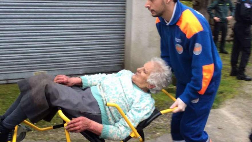 Un operario del 061, llevando a la mujer a la ambulancia para su traslado al centro de salud. // Faro