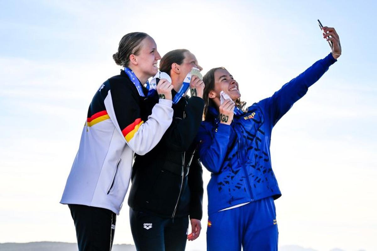 Paula Otero, con el móvil en la mano, se hace una foto junto a Moesha Johnson e Isabel Gose en el podio de Cerdeña.