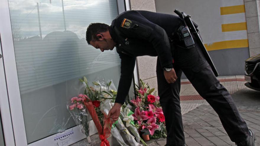 Un policía deposita flores en la entrada de la sucursal atracada // Marta G. Brea