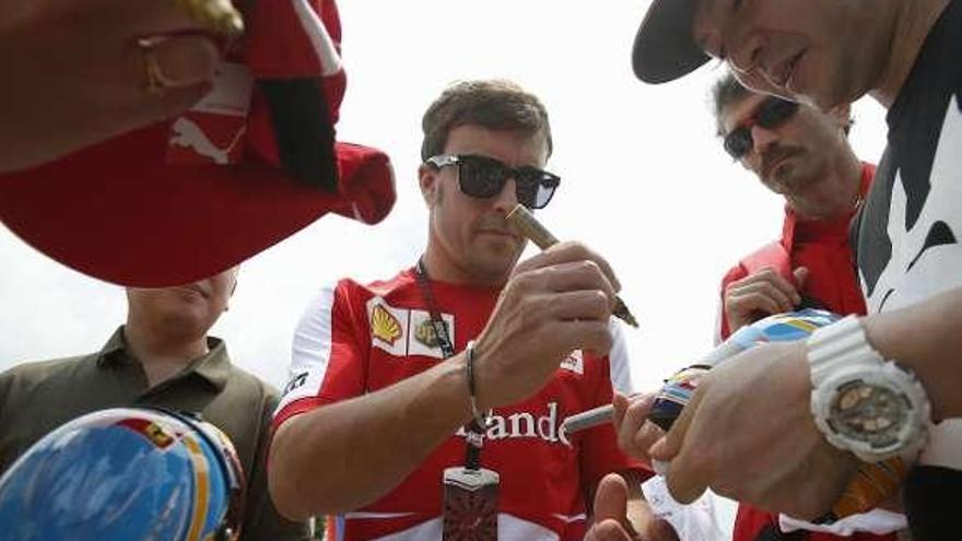 Fernando Alonso firma autógrafos, ayer en Sepang. // Reuters