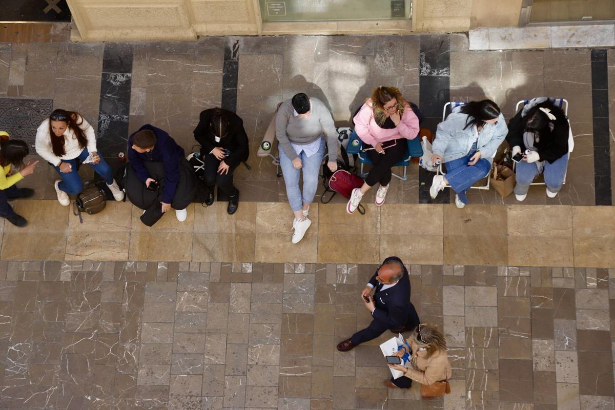 MLG 30-03-2026.-Varias personas esperan sentadas en las calles de la capital con sus propias sillas, para ver las procesiones, donde están prohibidas por un bando del ayuntamiento de la capital