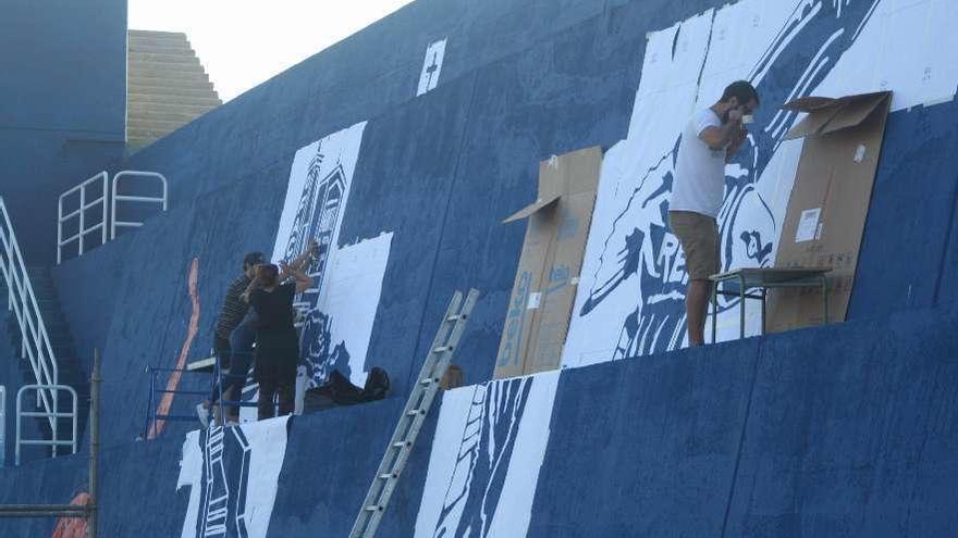 Artistas y colaboradores en pleno trabajo sobre el &quot;lienzo&quot; azul del espigón del puerto guardés. // C.A.G.
