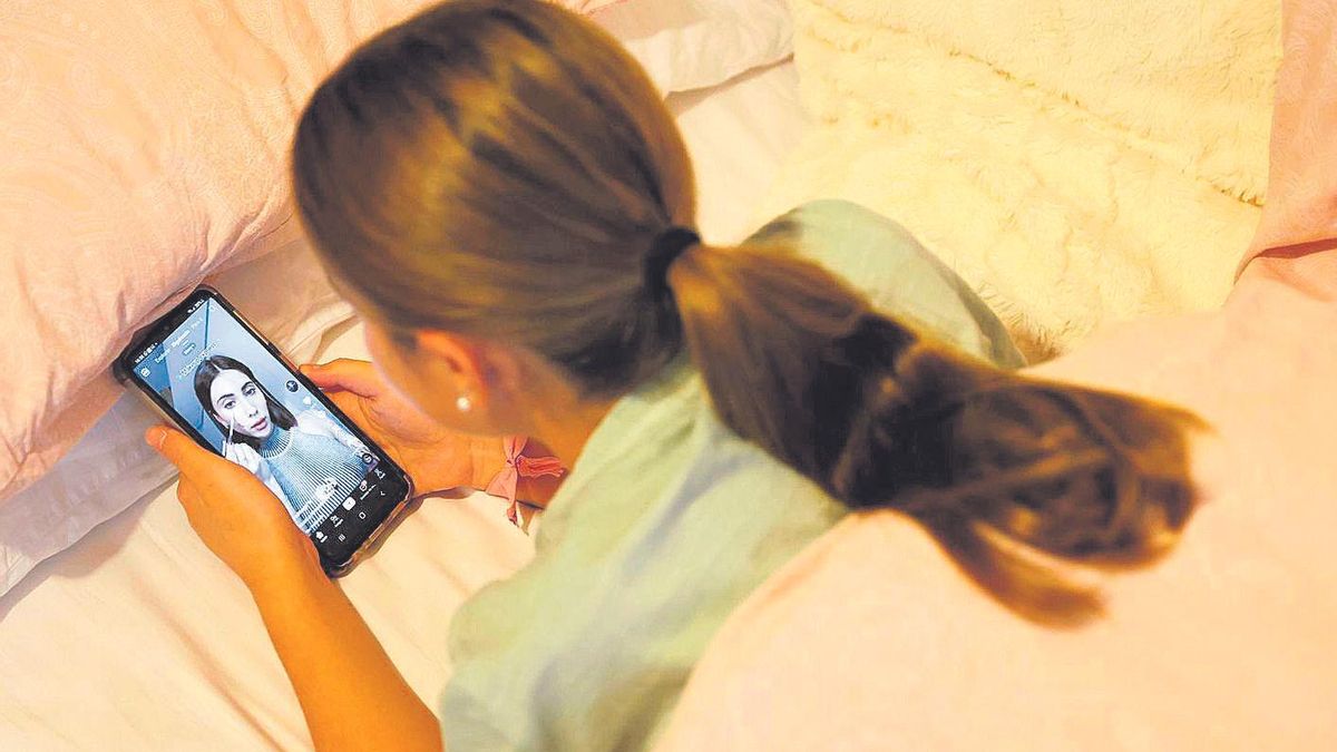 Una adolescente observa a una ‘influencer’ en TikTok en su teléfono móvil desde la cama