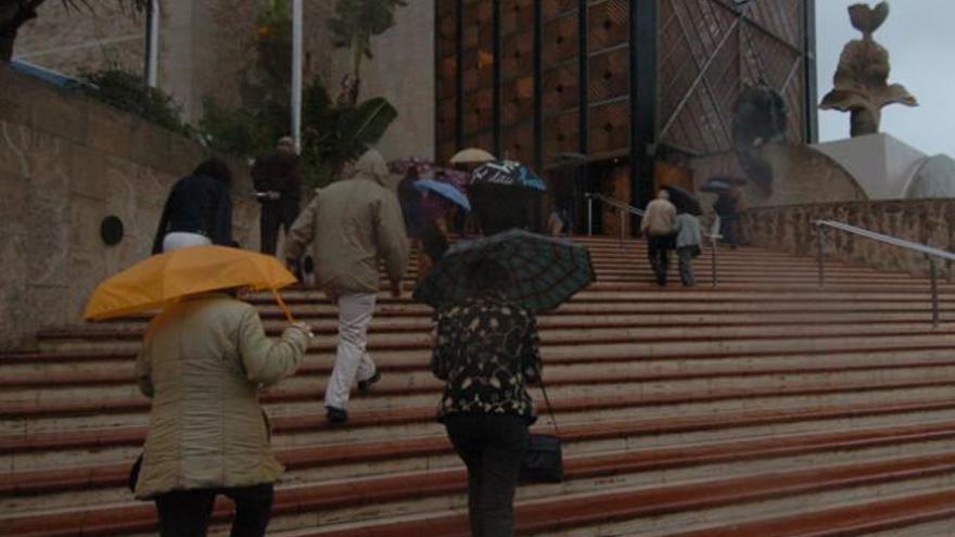 Varias personas acceden al Auditorio Alfredo Kraus con paraguas. i  MARRERO