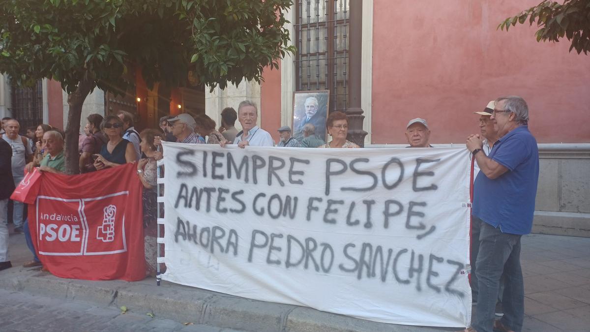 Militantes del PSOE andaluz despliegan su pancarta y colocan una foto de Pablo Iglesias para recibir a Felipe González en Sevilla.