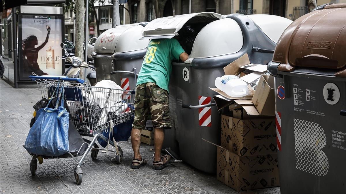 Un hombre busca en unos contenedores en el Eixample de Barcelona.