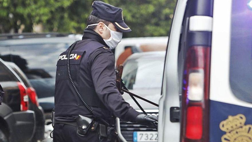 Un agente introduce en un vehículo policial los dos rifles de balines confiscados al detenido.