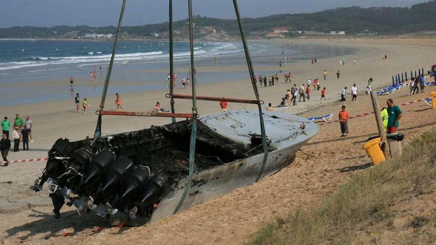 Una grúa eleva los restos de la lanzadera quemada en A Lanzada en la mañana del 15 de agosto de 2008. // Muñiz