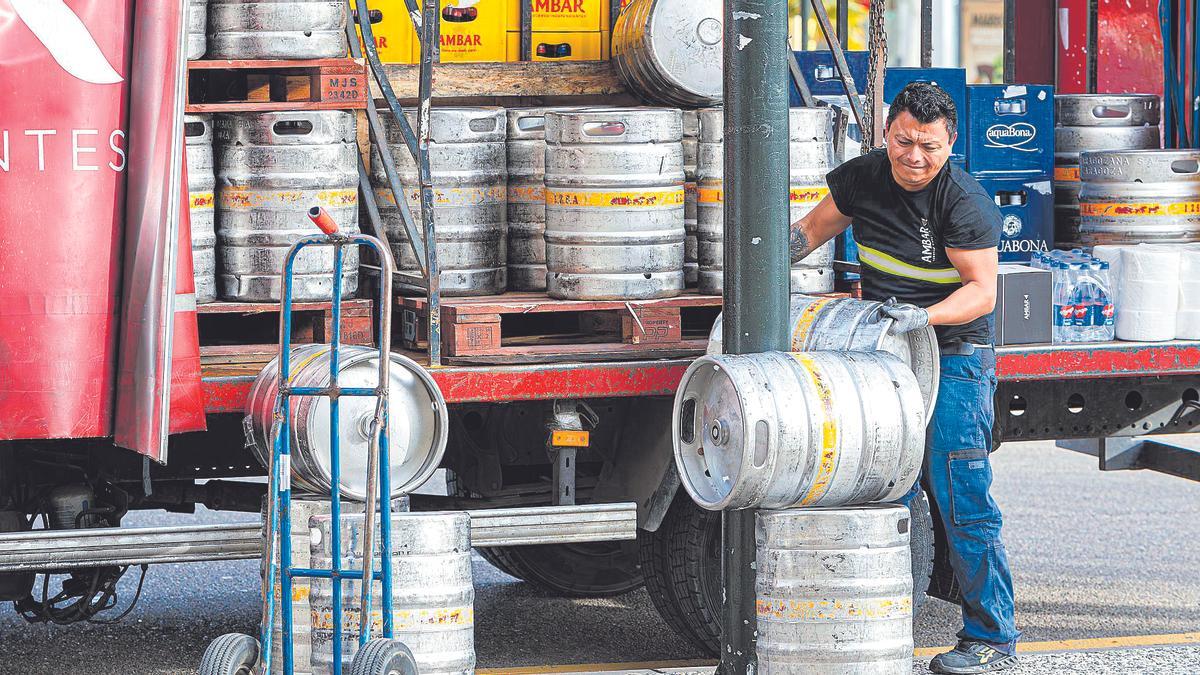 Un repartidor descarga un camión lleno de barriles de cerveza.