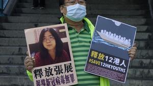 Un activista a favor de la democracia sostiene pancartas con la imagen de la bloguera china Zhang Zhan frente a la oficina de representación del Gobierno chino, en Hong Kong.