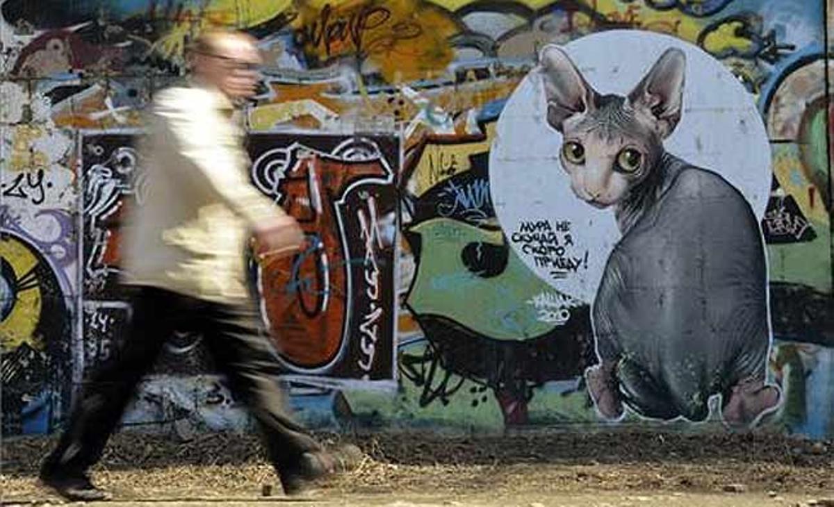 Un home camina davant el grafit d’un mur, a la ciutat de Vladivostok (Rússia).