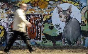 Un home camina davant el grafit d’un mur, a la ciutat de Vladivostok (Rússia).