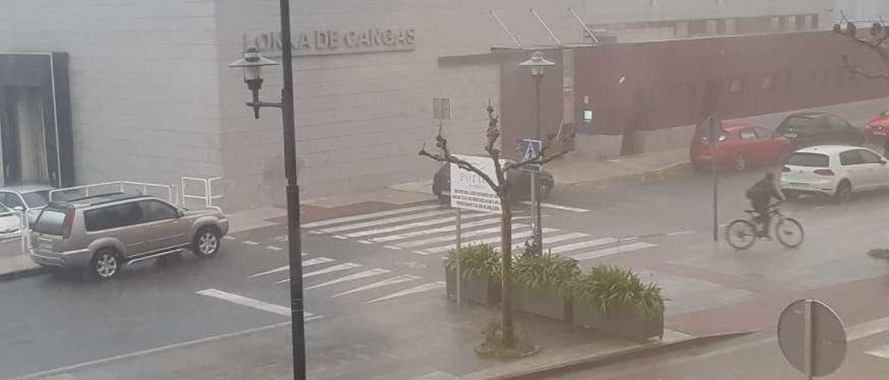 Pedaleando bajo la lluvia. Es amor a la bicicleta o es obligación, pero lo cierto es que al ciclista que ayer cruzaba por delante de la Lonja de Cangas bien poco le importaba la tromba de agua que estaba cayendo en ese momento. Es nuestro Gene Kelly al más puro estilo de Broadway. S.Á.