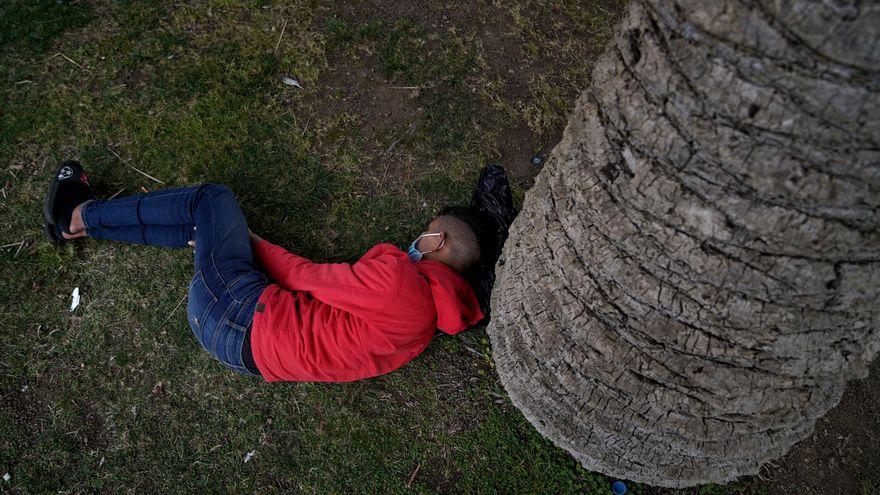 Un joven migrante duerme en un parque cercano al puerto de Ceuta.