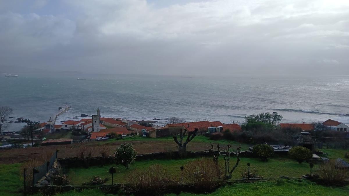 Una vista del lugar de  Curro, con el temporal en  el mar y el muelle de la  isla de Ons en la jornada del viernes.