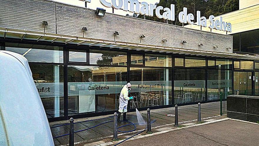 Un treballador desinfectant l&#039;entrada del centre sanitari.