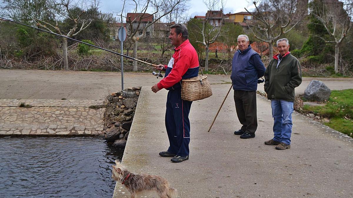 Un pescador de Rionegro del Puente prueba suerte con la caña ante la mirada de dos vecinos. | Araceli Saavedra