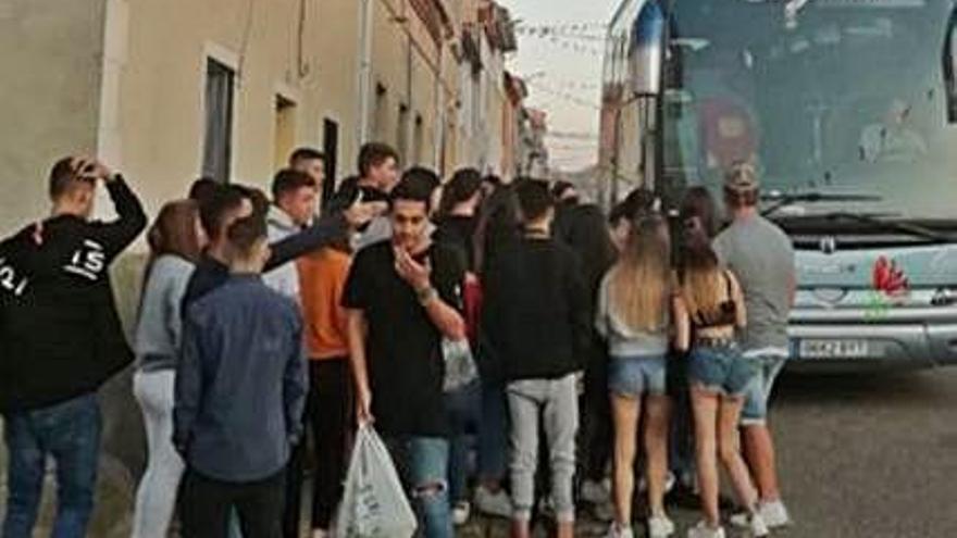 Jóvenes esperan en un pueblo a que el autobús les lleve a su destino.