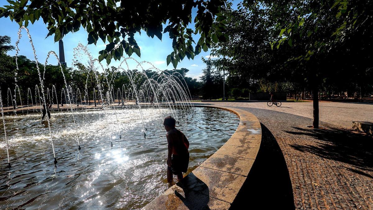 Un niño se refresca en una fuente durante una ola de calor en Madrid.