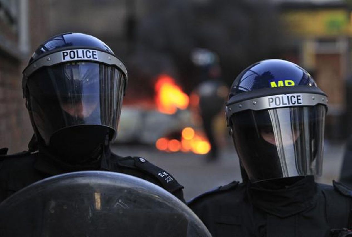 Antiavalots de la policia de Londres mantenen un cordó policial davant un vehicle incendiat a Hackney, est de Londres (Anglaterra).