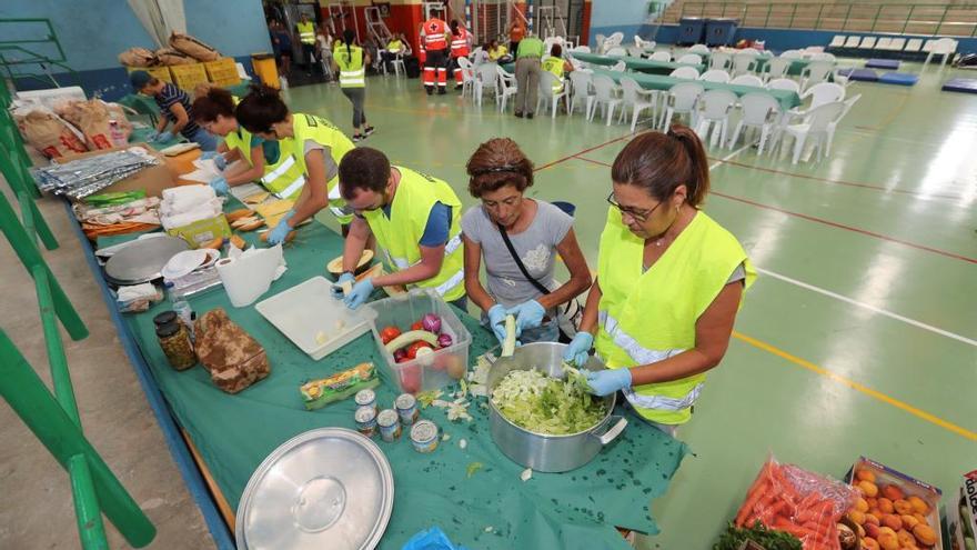 Varios voluntarios preparan comida para los damnificados del incendio en el polideportivo municipal de Agaete.