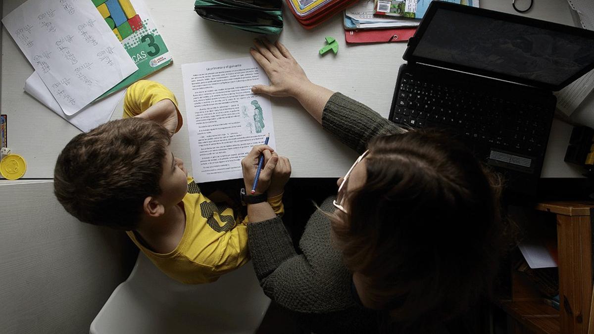 Una mujer ayuda a su hijo a hacer los deberes, el pasado 15 de abril, en pleno confinamiento, en Madrid