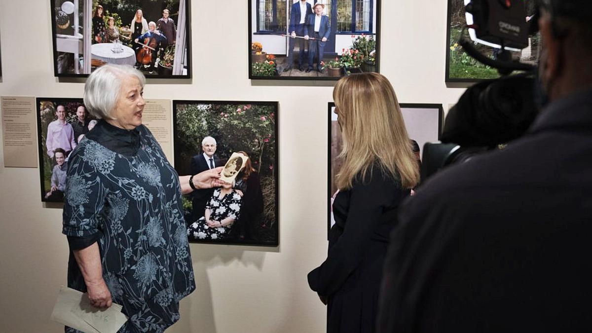 Joan Salter mostra a la premsa una foto de quan era nena davant d’un seu retrat recent, en la presentació de l’exposició del Museu de la Guerra de Londres.  | IWM