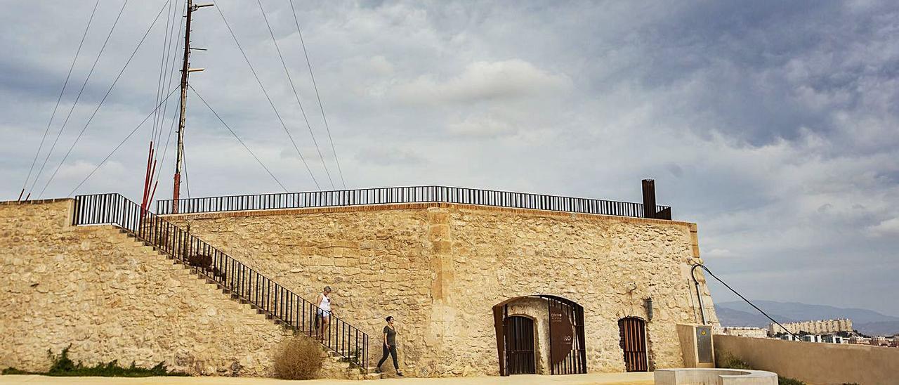 Una pareja pasea por la atalaya; a la derecha, la puerta de recepción de visitantes cerrada