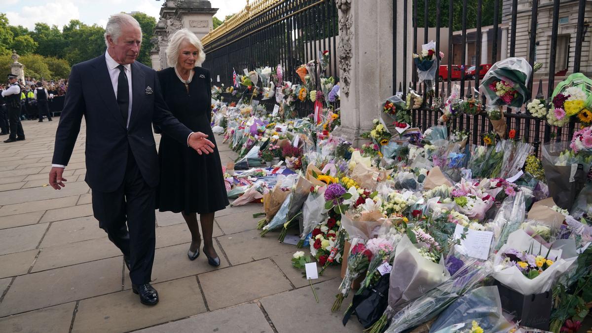 El Rey Carlos III y Camilla, la Reina Consorte, miran las flores fuera del Palacio de Buckingham, Londres, tras la muerte de la Reina Isabel II.