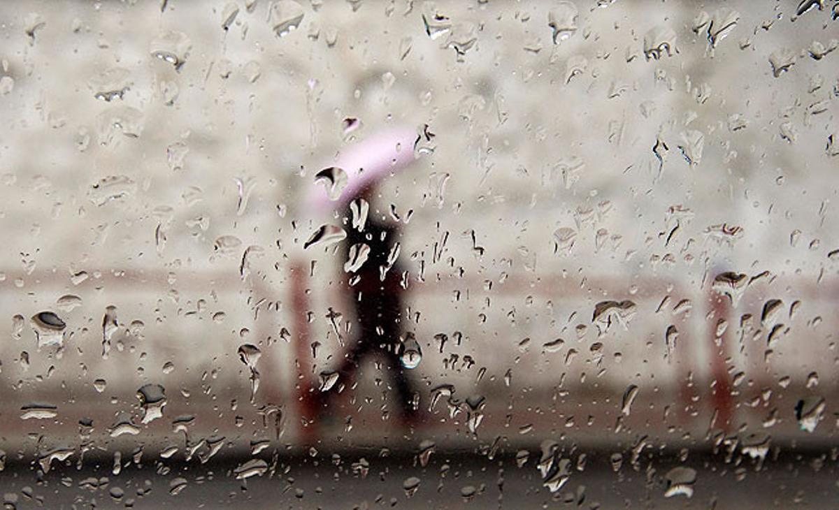 Una persona camina pel carrer en un dia plujós. Oix, Kirguizistan.