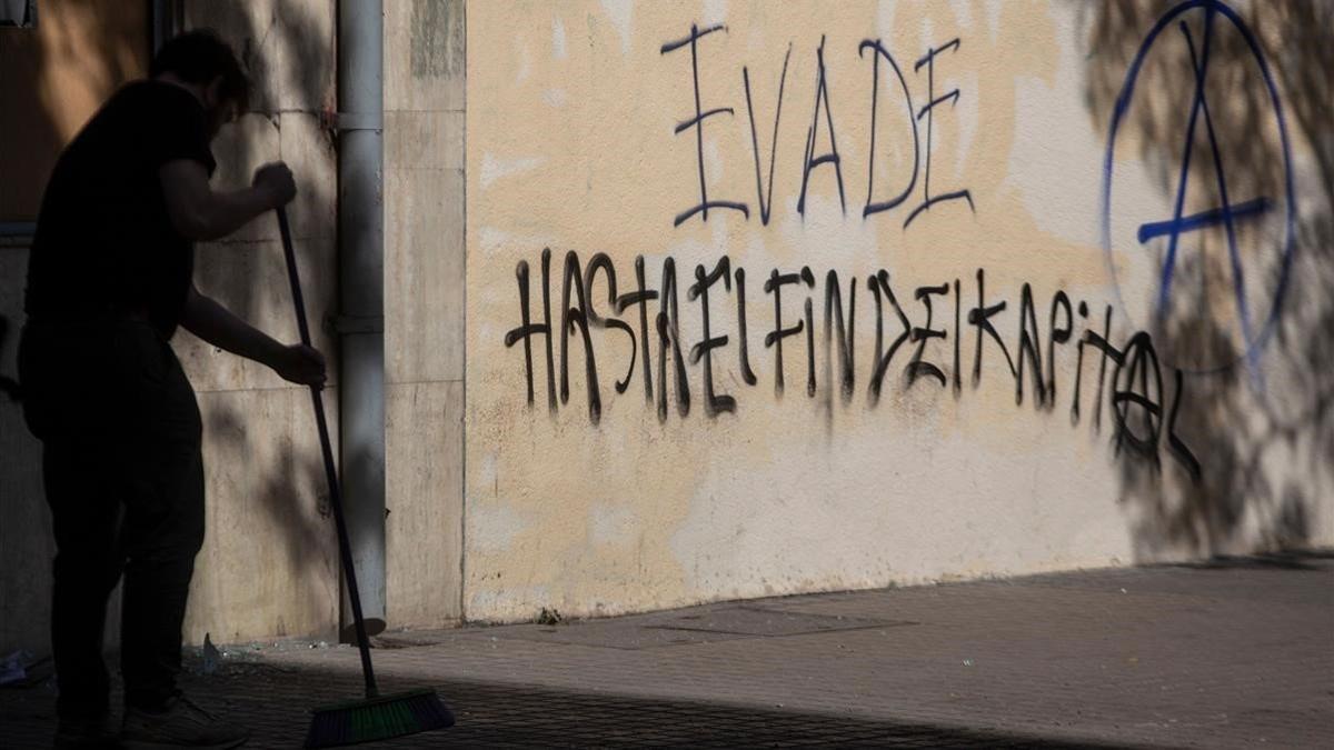 Un hombre barre el suelo ante un grafiti que reivindica la 'evasión', en una calle de Santiago de Chile.