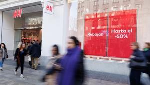 Archivo - Varias personas caminan frente a una tienda de H&M