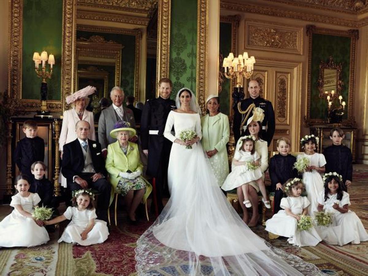 Retrato familiar el día de la boda de los duques de Sussex, 21 de mayo de 2018. Sentada, a la derecha, con su hija Carlota en las rodillas, Kate Middleton tuvo que transigir con el largo del vestido de las niñas que quiso Meghan, en contra del protocolo.