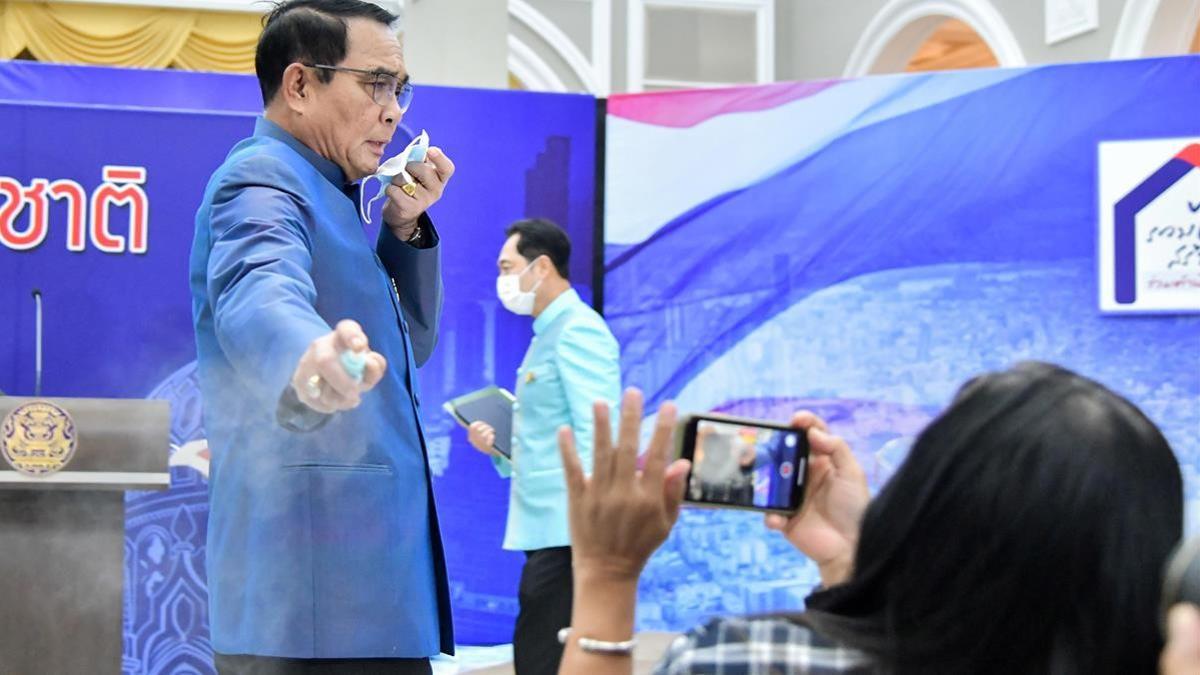 El primer ministro de Tailandia, Prayuth Chan Ocha, rocía con gel hidroalcohólico a un grupo de periodistas este martes, en Bangkok