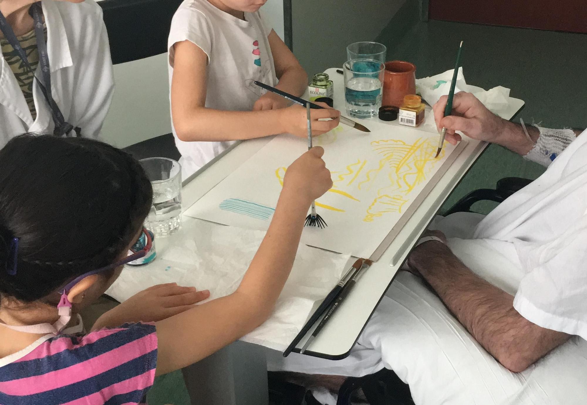 Carles Olivé pinta junto a sus dos hijas durante una sesión de arteterapia en el Hospital de Sant Pau