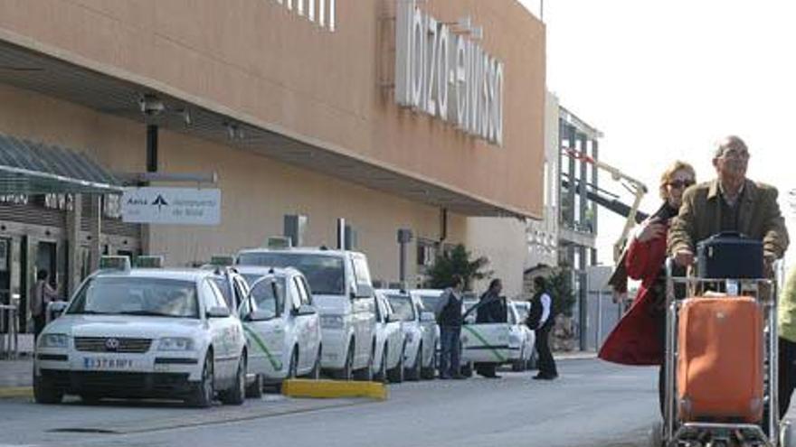 Varios taxis esperan clientes en la parada del aeropuerto.