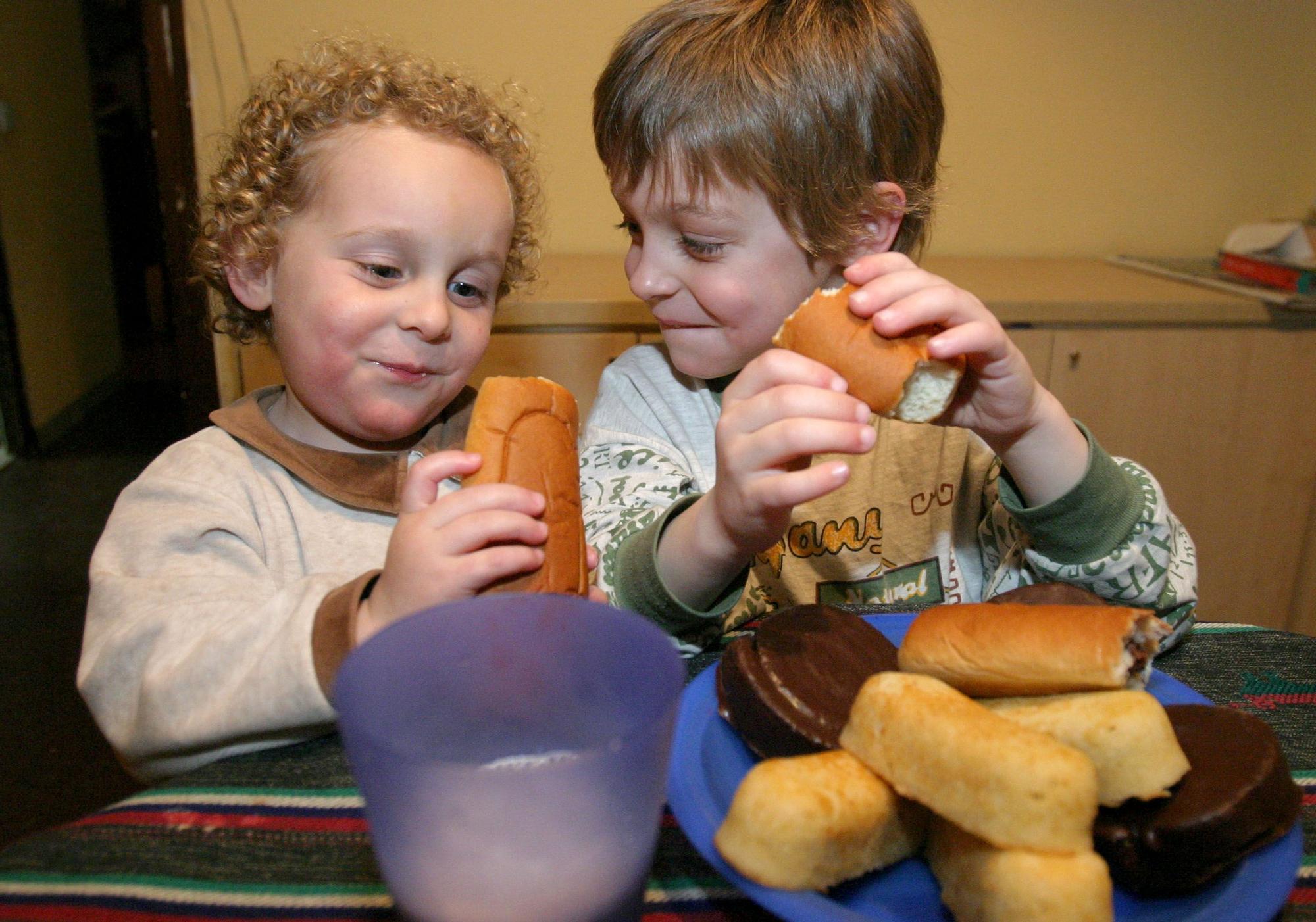 Dos niños comiendo bollería.