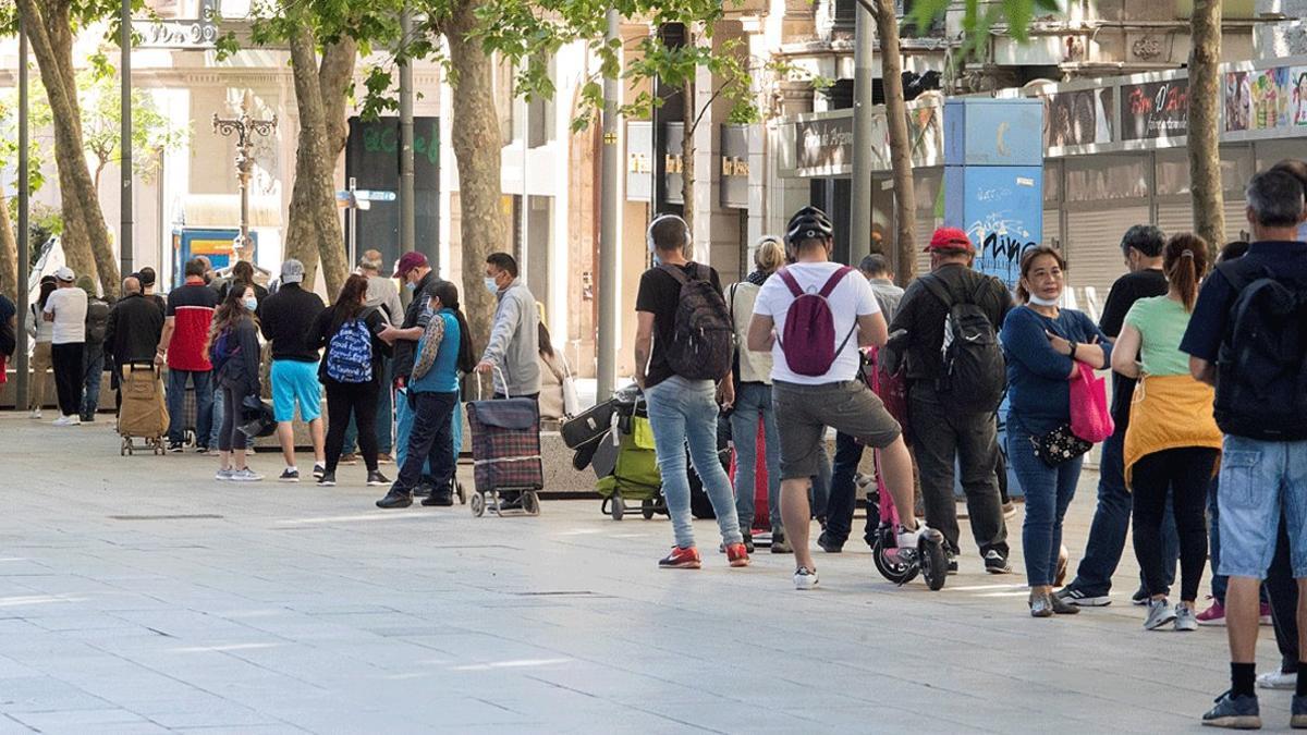 Larga cola de personas en situación del vulnerabilidad que esperan para recoger comida en la parroquia de Santa Anna de Barcelona, el pasado 18 de mayo