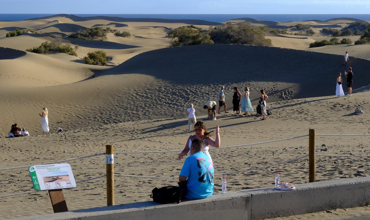 Turistas paseando en las dunas de Maspalomas fuera de los senderos delimitados.
