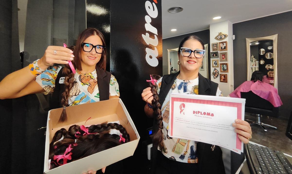 Balbi Castrosín (izquierda) y Judith Rodríguez, con las coletas y la caja que envían cuando está llena, en su peluquería de Oviedo.
