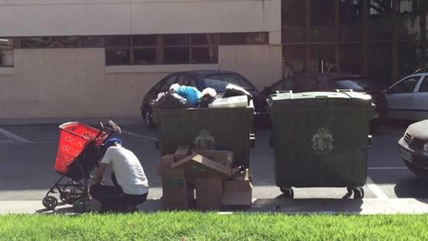 Imagen de un hombre rebuscando junto a un contenedor de basura en la Plaza de Santiago.