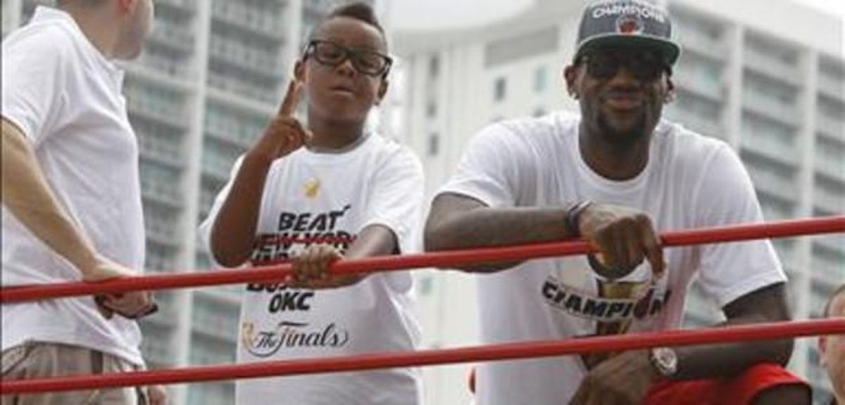 Lebron James, amb el seu fill Lebron Jr. al sostre d’un dels autobusos de la rua.
