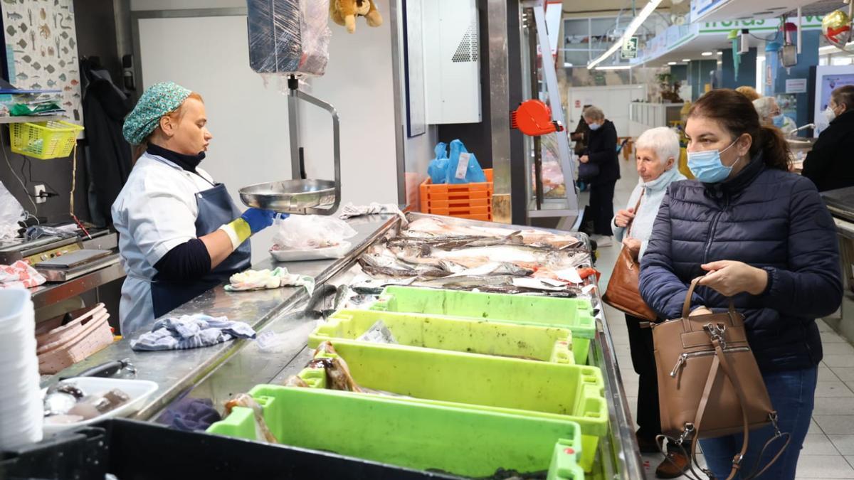 Personas con y sin mascarillas en una pescadería de un mercado de Vigo.